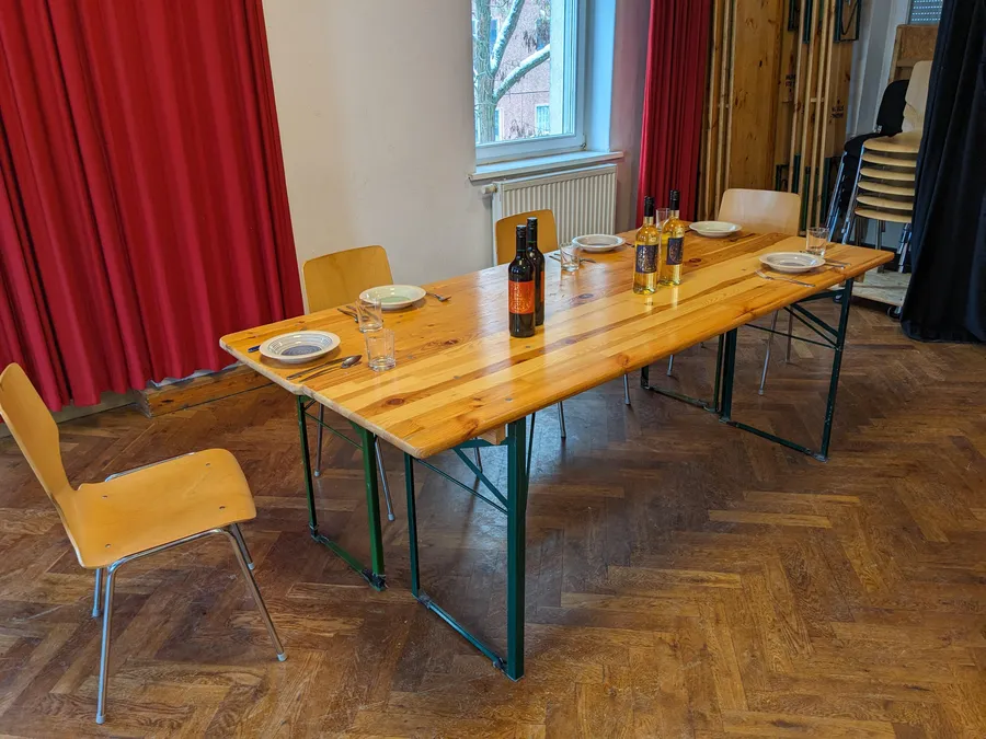 Langer Tisch mit Gedecken und Weinflaschen